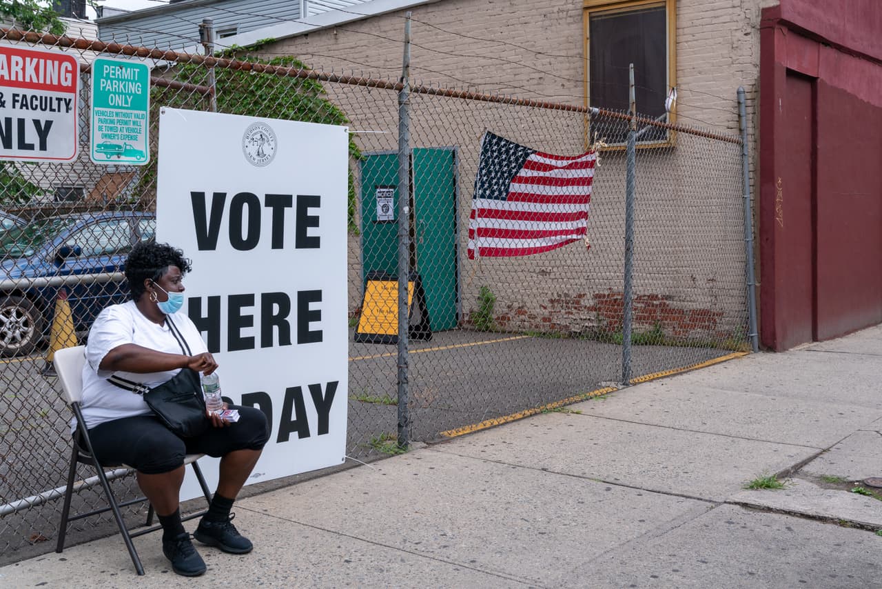 Un trabajador electoral se sienta afuera de la mesa electoral en Saint Aloysius el 7 de julio en Jersey City, Nueva Jersey. La elección primaria será una prueba para el movimiento progresista del estado que busca varios escaños en la Cámara y el único puesto del Senado en disputa.