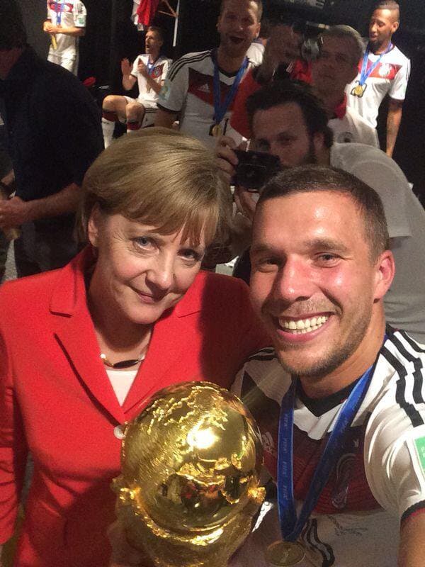 Lukas Podolsky y la canciller Ángela Merkel con la Copa del Mundo.