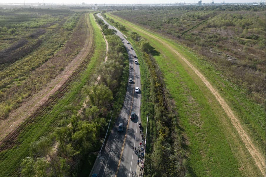 Los participantes del recorrido en bicicleta hacen una parada en los vertederos creados a partir de la tierra dragada durante la ampliación del canal de navegación en el corredor petroquímico. Ha habido preocupación por posibles contaminantes en la tierra.