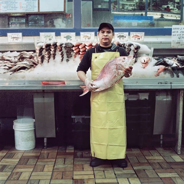 Pedro Ruiz, de 28 años, sostiene un pescado en el Sea & Sea Fish Market, en Harlem. Uno de sus trabajos es cortar los vegetales para la comida que se prepara en el lugar. Su forma preferida de cocinar pescado es a la veracruzana, como se hace en la costa este de México.