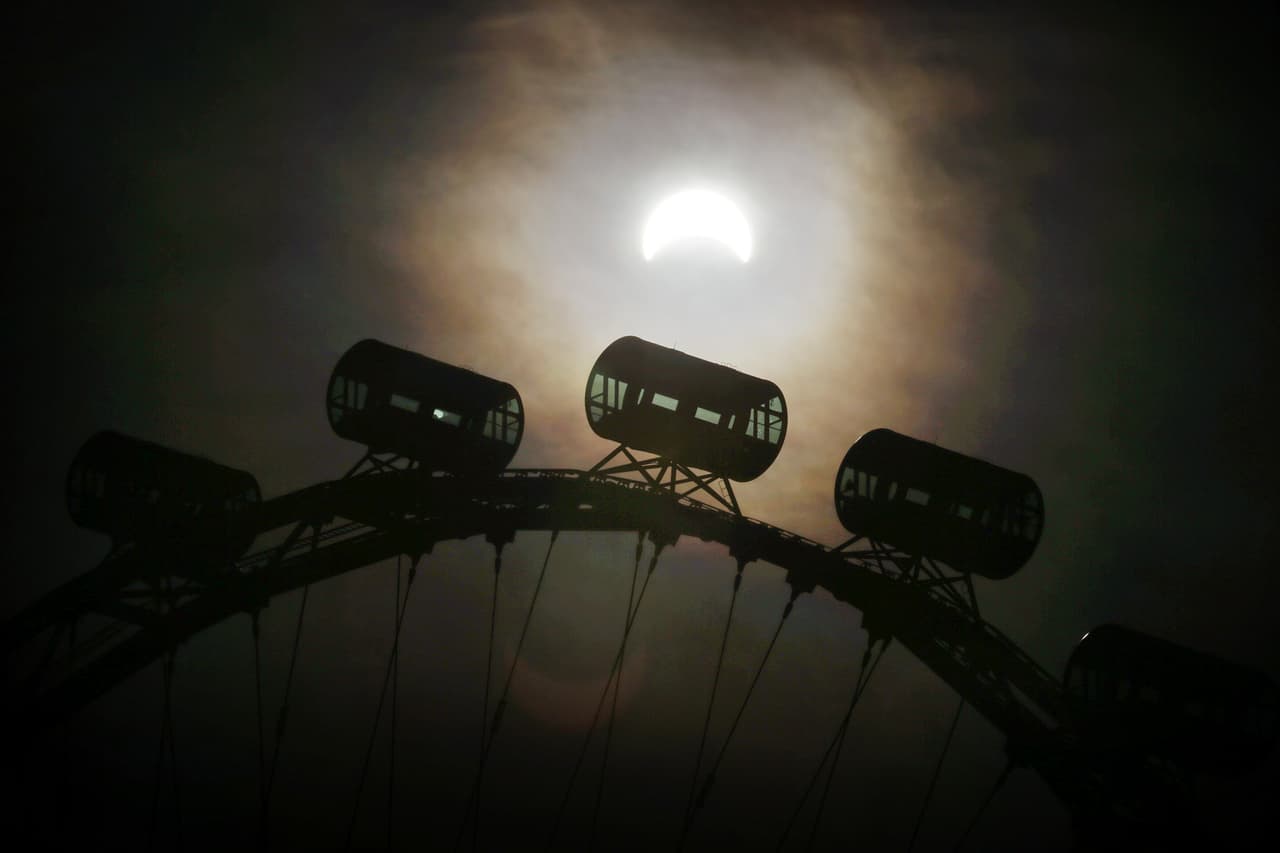 En esta imagen, el eclipse parcial puede observarse detrás de las cápsulas de pasajeros de Singapore Flyer, la rueda de la fortuna más alta del mundo, en Singapur.