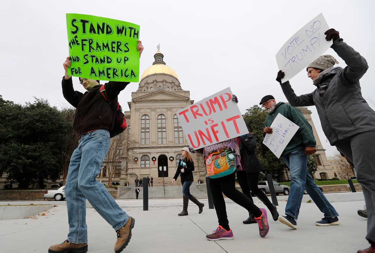 Ciudadanos estadounidenses se manifiestan afuera del Capitolio Estatal de Georgia, antes del encuentro de los dieciséis electores del estado, que emitirán sus votos este 19 de diciembre de 2016. El Colegio Electoral de EE.UU se reúne este lunes para certificar la victoria del republicano Donald Trump.