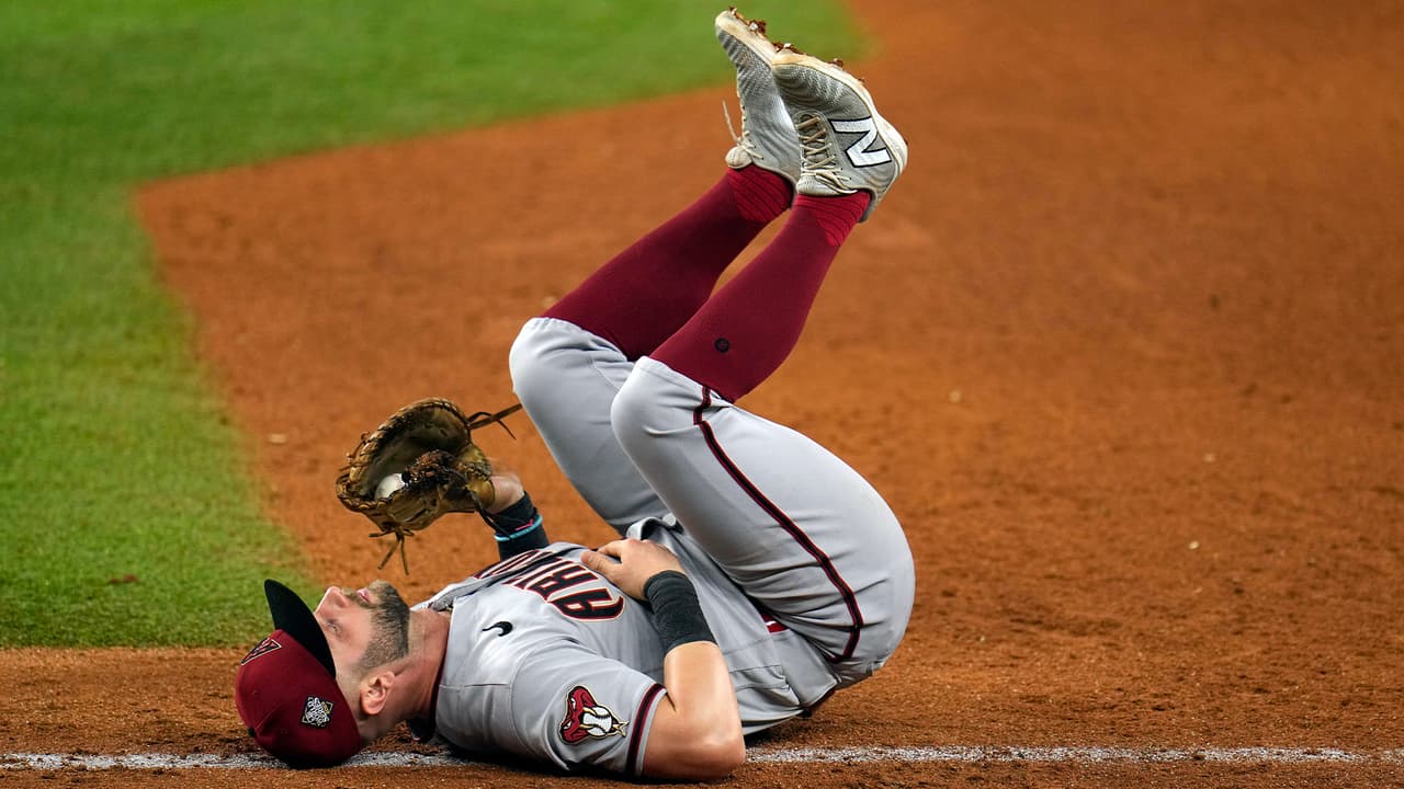 El primera base de los Arizona Diamondbacks, Christian Walker, cae hacia atrás después de estirarse para atrapar el lanzamiento y lograr un out en una bola rodada por Leody Taveras de los Texas Rangers durante la octava entrada del Juego 2 de la Serie Mundial de béisbol, el sábado 28 de octubre de 2023 en Arlington, Texas.