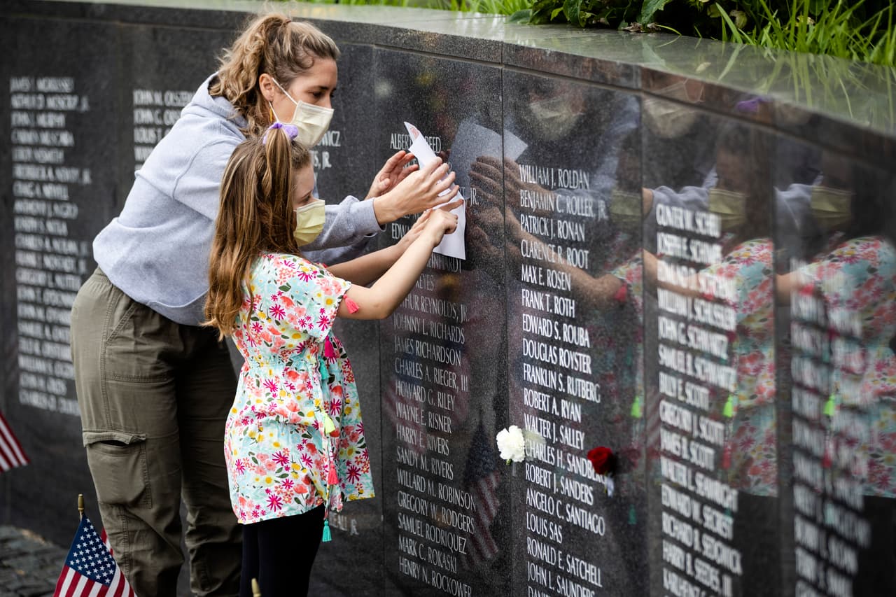 Maureen O'Neill y su hija Adalina, de 8 años, con máscaras protectoras como precaución contra el coronavirus, trazan en un papel el nombre de la amiga de su tío en el Vietnam War Memorial, en Filadelfia.
