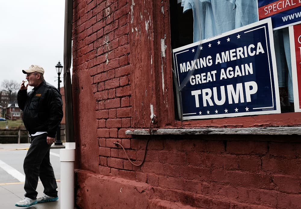 Un hombre camina junto a un cartel con el lema de campaña de Donald Trump en Waynesburg, Pennsylvania.