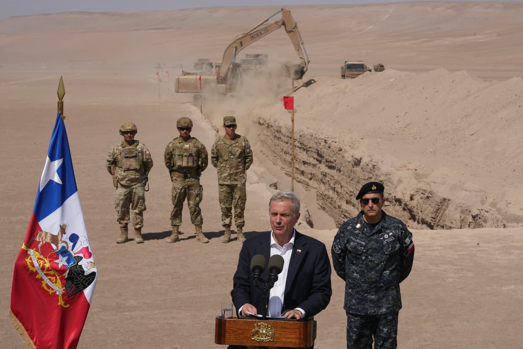 El presidente chileno José Antonio Kast ofrece una conferencia de prensa mientras una máquina excava, como parte de las medidas para disuadir la migración irregular, a lo largo de la frontera norte en el paso fronterizo de Chacalluta, en Arica, Chile, el lunes 16 de marzo de 2026.