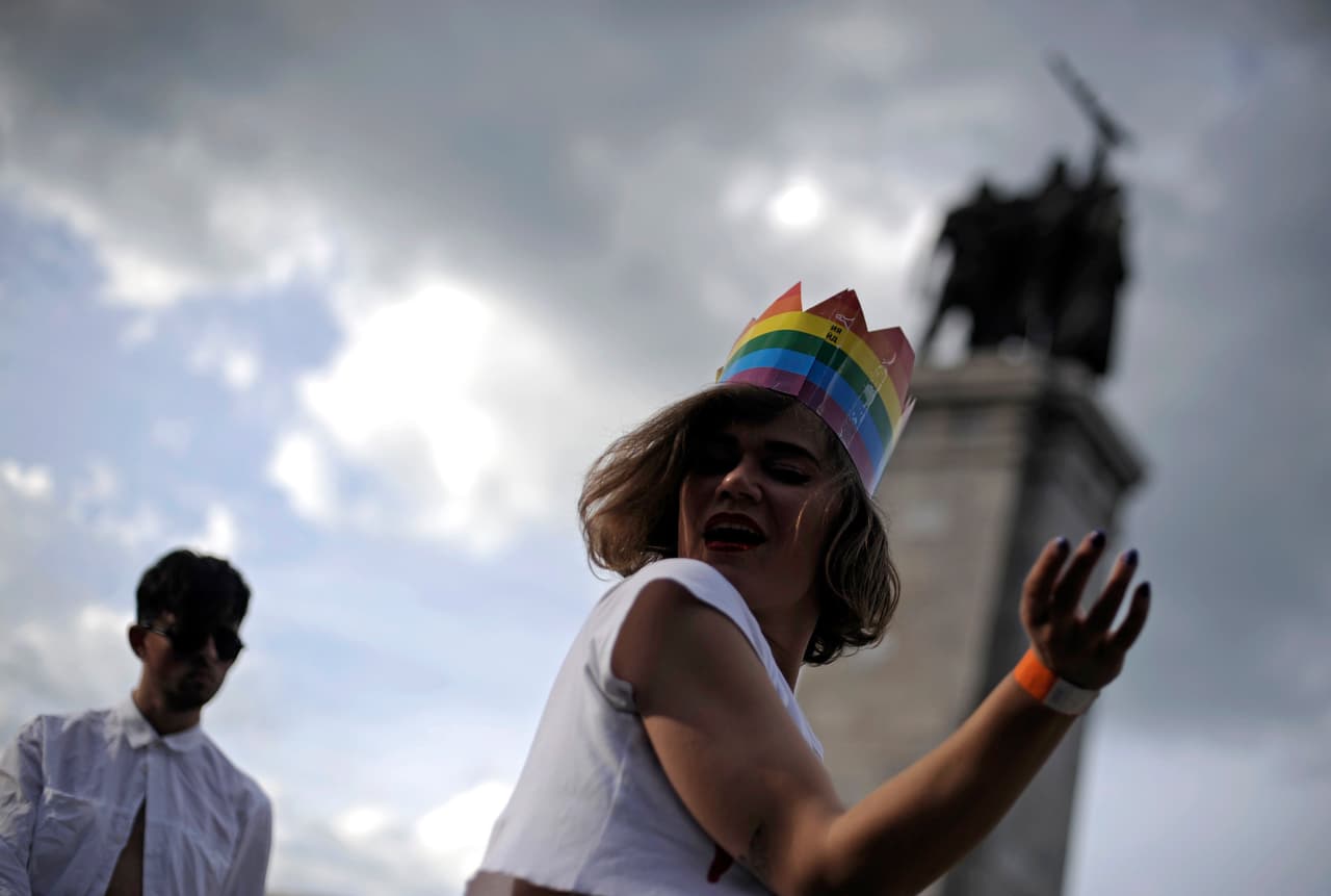 Una mujer con una corona de papel en la cabeza baila frente a un monumento en Sofía, Bulgaria.