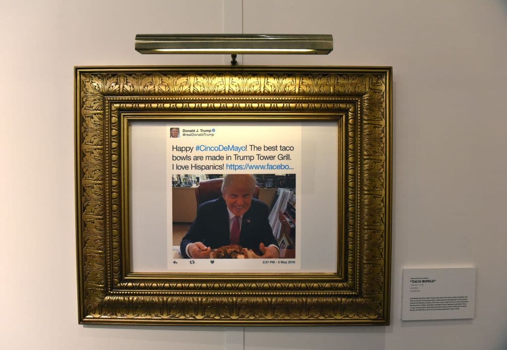 "¡Feliz Cinco de Mayo! Los mejores 
<i>taco bowls</i> son hechos en Trump Tower Grill. ¡Amo a los hispanos!" es la primera "obra maestra" que se aprecia al entrar a la biblioteca a modo de parodia. Este es uno de los tuits que mereció, según los curadores, ser enmarcado en color dorado, el favorito del presidente. Al lado, una bandera de Estados Unidos. Este tuit 
<b><a href="http://www.univision.com/noticias/elecciones-2016/trump-quiere-llegarle-a-los-hispanos-al-corazon-con-este-taco-bowl">fue publicado el 5 de mayo</a></b> (obviamente) de 2016, cuando se conmemora la Batalla de Pueba de 1862 y en lo que supuso un intento (¿infructuoso?) del mandatario por llegar a los votantes hispanos. (Drew Angerer/Getty Images)
