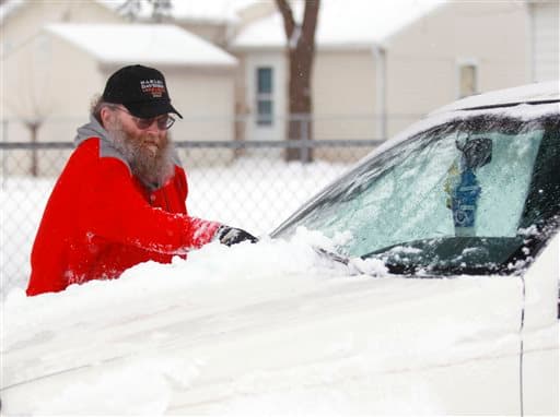 Rom Smith limpia su auto de la nieve en Iowa.