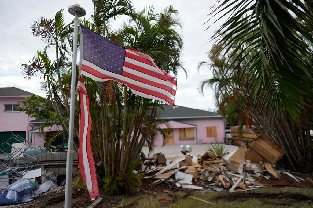 ARCHIVO - Una bandera americana desgarrada ondea fuera de una casa con muebles y enseres domésticos dañados por el huracán Helene apilados en el exterior, a lo largo de la calle a la espera de ser recogidos antes de la llegada del huracán Milton en Holmes Beach en Anna Maria Island, Florida, el 8 de octubre de 2024. (Foto AP/Rebecca Blackwell, Archivo)