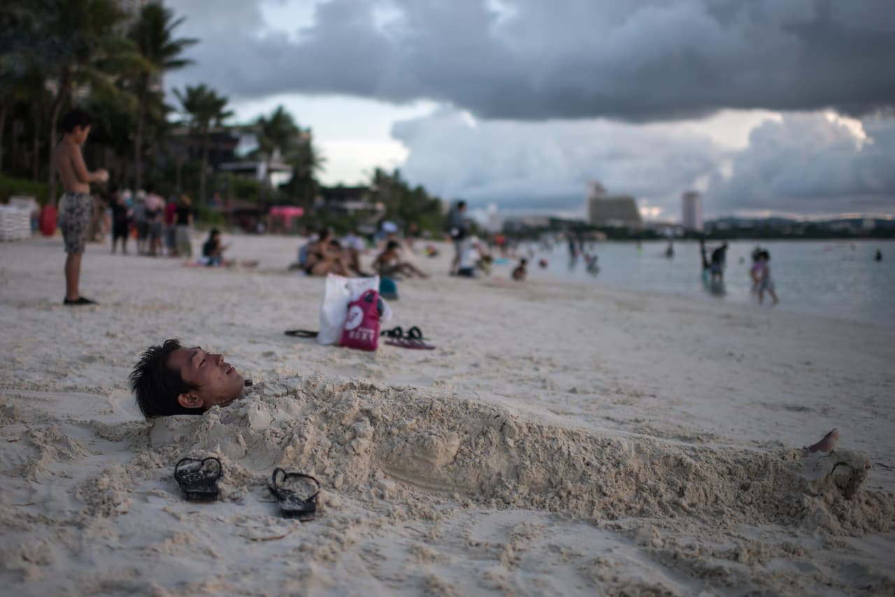 Un hombre cubierto de arena en una playa de la bahía de Tumon, el 15 de agosto. Luego de las amenazas de bombardeo por parte de 
<b><a href="http://www.univision.com/temas/corea-del-norte" target="_blank">Corea del Norte</a></b>, el presidente 
<b><a href="http://www.univision.com/temas/donald-trump" target="_blank">Donald Trump</a></b> le dijo al gobernador de la isla Eddie Calvo que estas tensiones servirían para elevar los números del turismo en Guam.