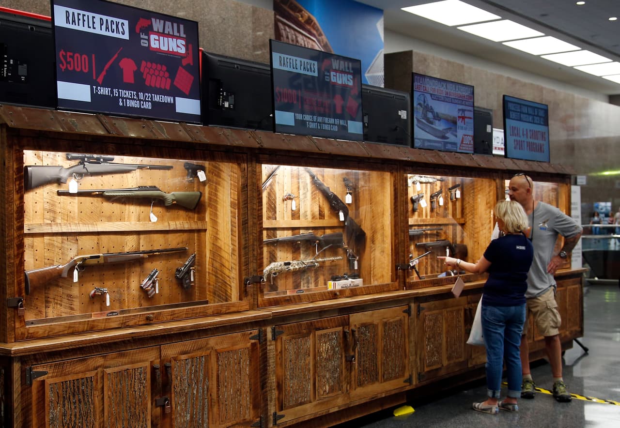 Marilyn Olliver, izquierda, y su esposo Robert, de Orlando, Florida, observan los artículos que serán rifados en la convención de la NRA en Dallas.