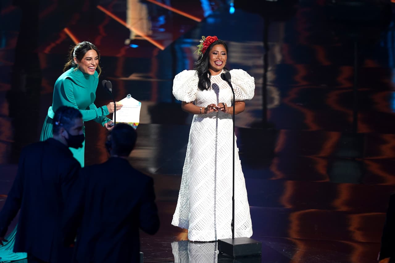 Para presentar el premio a Mejor Álbum de Música Ranchera/Mariachi en el escenario junto a Ana Brenda Contreras, Yalitza eligió un vestido de la diseñadora venezolana 
<a href="https://www.carolinaherrera.com/us/en/" target="_blank">Carolina Herrera</a> en petatillo blanco de organdí, cuello redondo y mangas abullonadas.