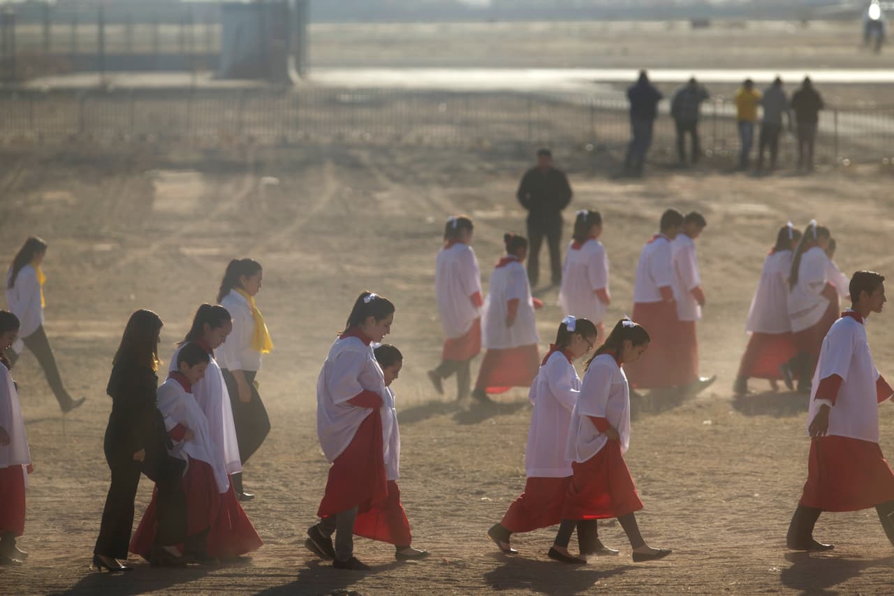 Los niños del coro caminan atraviesan un área de terracería en el aeropuerto.