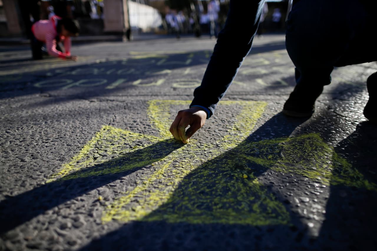Carlos Domínguez pinta una cruz de tiza en las calles de Juárez mientras espera el paso del Papa.