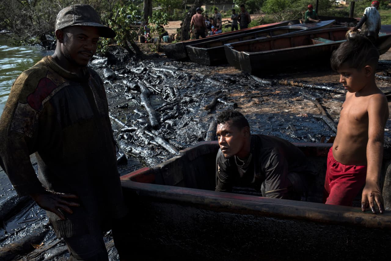 Los pescadores Erick ALejandro (izq) y Kelvin Alcalá quitan el petróleo acumulado dentro del bote al finalizar la jornada. Los residentes locales dicen que la primera vez que vieron manchas de petróleo en la orilla fue a comienzos del gobierno de Chávez, cuando la industria petrolera empezó a deteriorarse.
<a href="https://www.univision.com/noticias/crisis-en-venezuela/cinco-de-los-seis-acusados-por-corrupcion-en-venezuela-vinculados-a-la-petrolera-pdvsa-tienen-nacionalidad-de-eeuu">El socialista sustituyó la estructura de méritos en la organización de PDVSA por el clientelismo político</a> y muchos de los ingenieros y gerentes, formados en universidades públicas del país y en el exterior, emigraron. Finalmente la infraestructura cayó en el deterioro y el desuso.