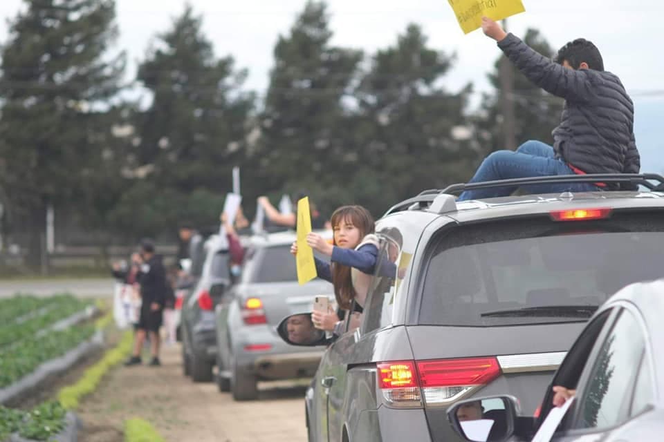 Desde la seguridad de sus automóviles, los participantes pusieron música y levantaron carteles para saludar a los trabajadores agrícolas, que a esa hora de la mañana trabajaban los campos.