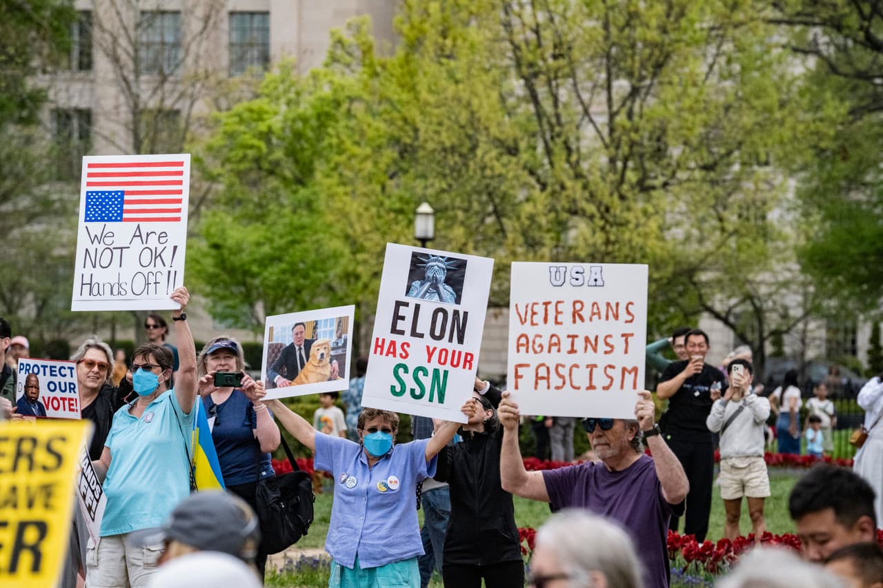 Manifestantes sostienen carteles en los que se lee "Veteranos contra el fascismo" y "ELON tiene tu SSN" en una manifestación en Washington, D.C., el 19 de abril de 2025. La manifestación se centra en el plan de deportación del ICE de Donald J. Trump que afecta a los campus universitarios y las comunidades locales.