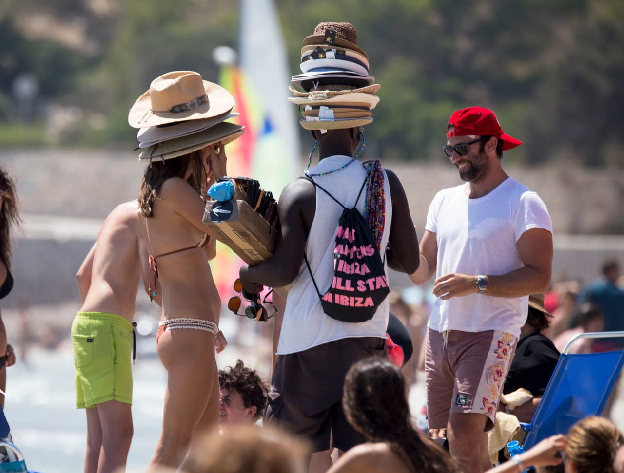 Alessandra Ambrosio lleva más de una semana en las playas de Ibiza disfrutando del verano español. Aquí, la modelo de 36 años bromea con un vendedor de sombreros en la playa.