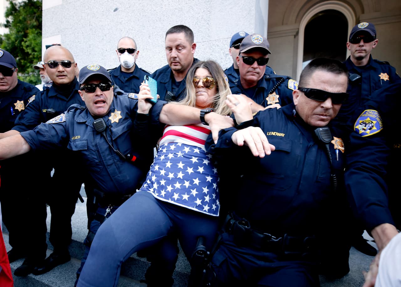 Oficiales citaron a varios manifestantes afuera del Capitolio estatal en Sacramento por violar la orden de quedar en casa. Después de varias horas de la protesta, los oficiales forzaron a las personas a las banquetas y dispersaron a los que llegaron a la reunión. (AP Photo/Rich Pedroncelli)