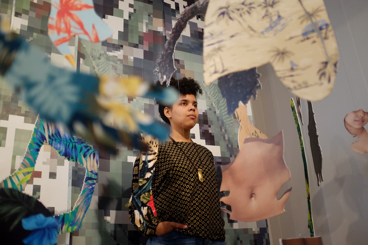 Joiri Minaya, una artista dominicana-estadounidense, se para detrás de la instalación #dominicanwomengooglesearch. Foto de Bianca Colón.