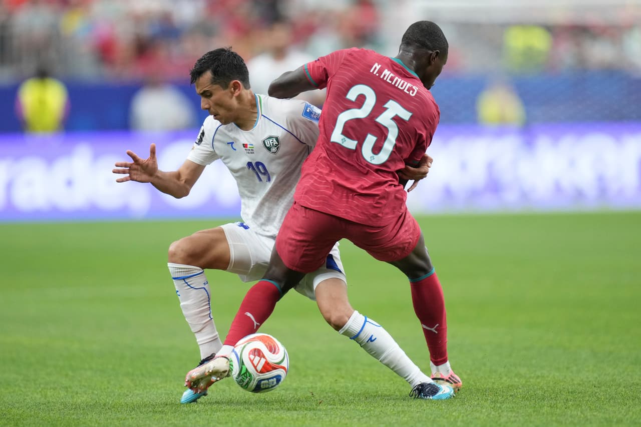 Nuno Mendes (25) de Portugal disputa el balón con Azizjon Ganiev (19) de Uzbekistán durante el partido de fútbol del Grupo K de la Copa Mundial entre Portugal y Uzbekistán