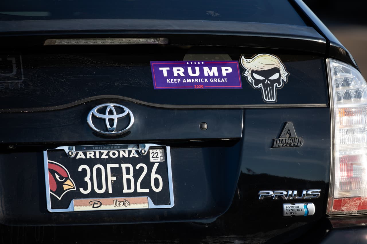 El automóvil de una persona tiene una calcomanía de Keep America Great y una de Punisher con el pelo del presidente Donald Trump antes de un mitin de campaña en Prescott, Arizona.