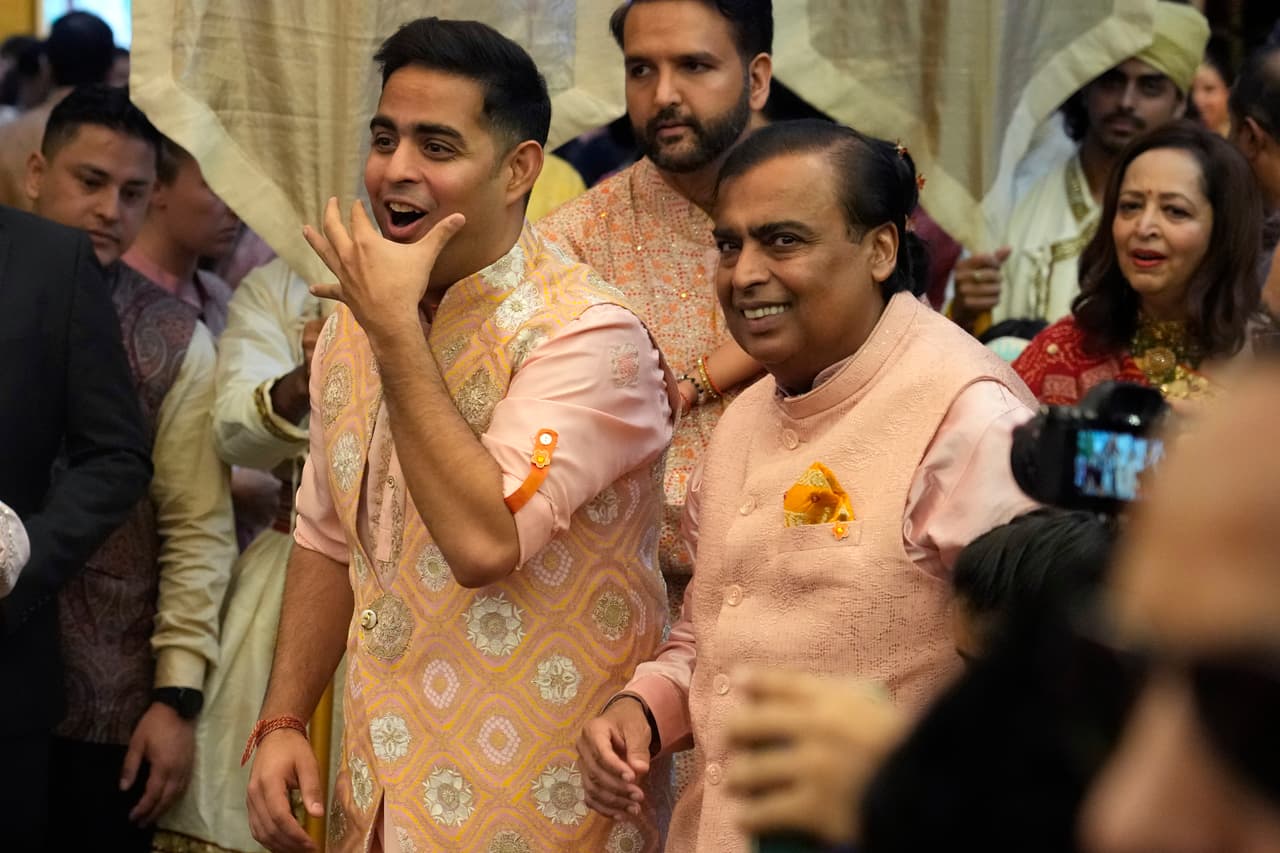 El presidente de Reliance Industries Limited, Mukesh Ambani, a la derecha, junto con su hijo Akash Ambani saludan a los invitados durante la ceremonia previa a la boda del hijo menor de Ambani, Anant Ambani, con Radhika Merchant, en su residencia Antilia en Mumbai, India, el miércoles 3 de julio de 2024.