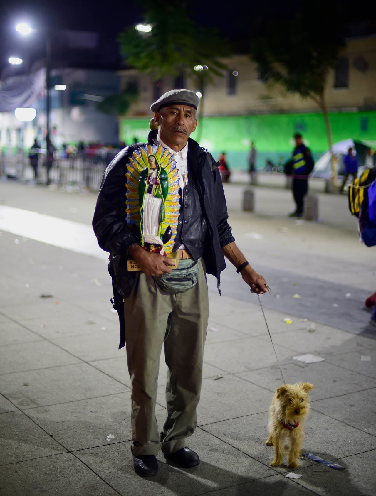Un seguidor camina rumbo al templo de Guadalupe con una imagen y su mascota.
