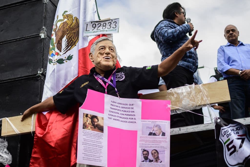 Un conductor de taxi con una máscara del presidente mexicano Andrés Manuel López Obrador forma parte de las protestas en el Zócalo de la ciudad.