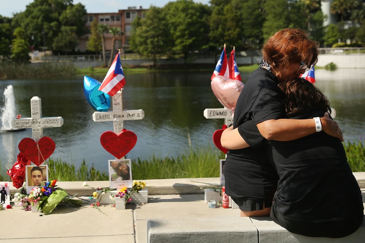 Dos mujeres se abrazan frente a las cruces puestas en memoria de los fallecidos en la masacre de Orlando.