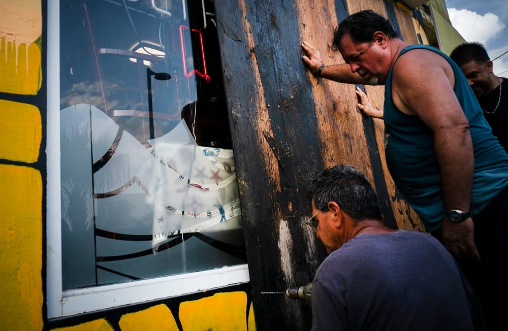 Dos hombres tapan las vidrieras de una tienda antes de la llegada de Dorian a Boquerón, Puerto Rico.