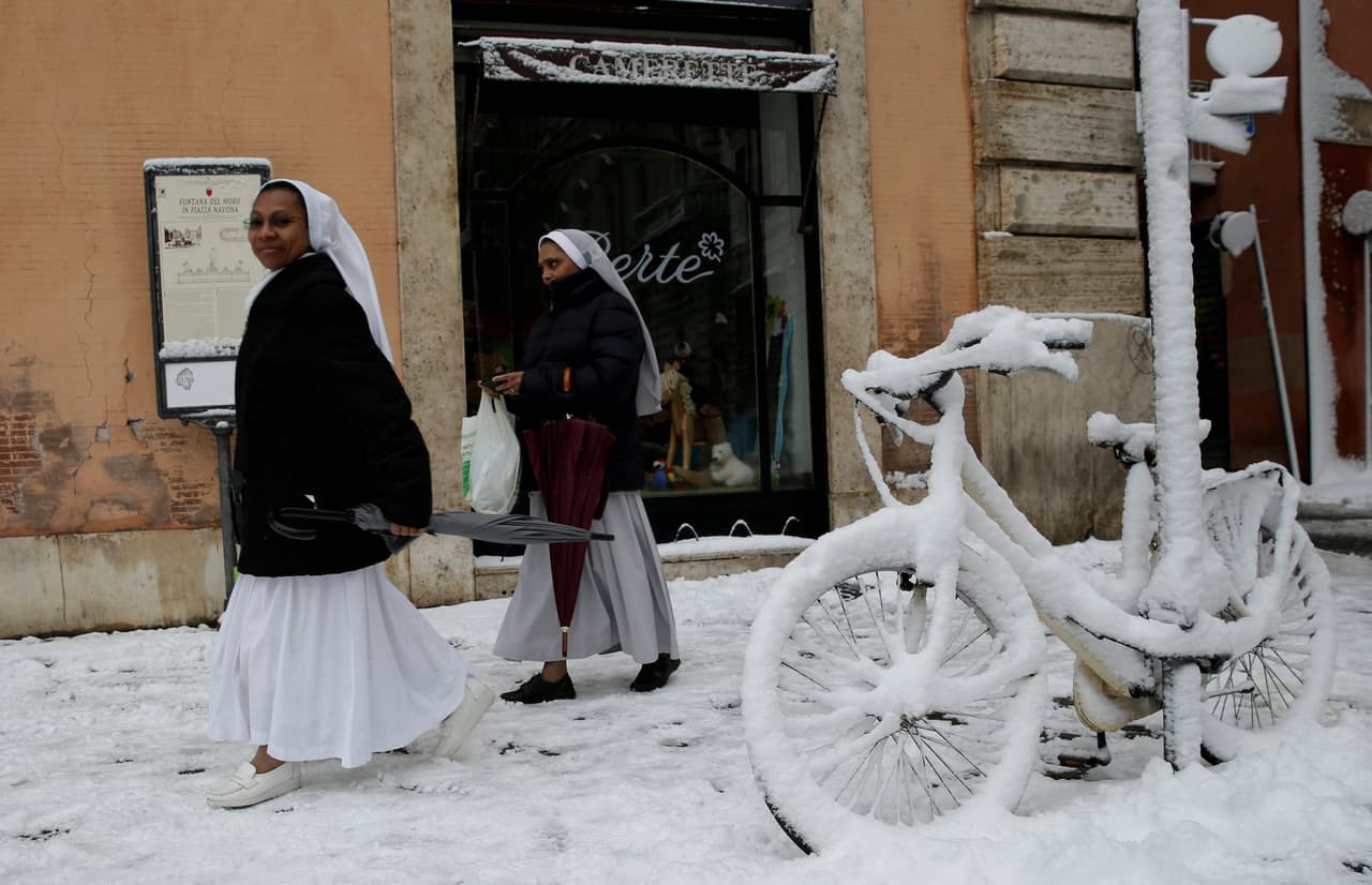 Dos religiosas caminan por una de las calles de la capital italiana, al lado de una bicicleta totalmente cubierta por una gruesa capa de nieve.