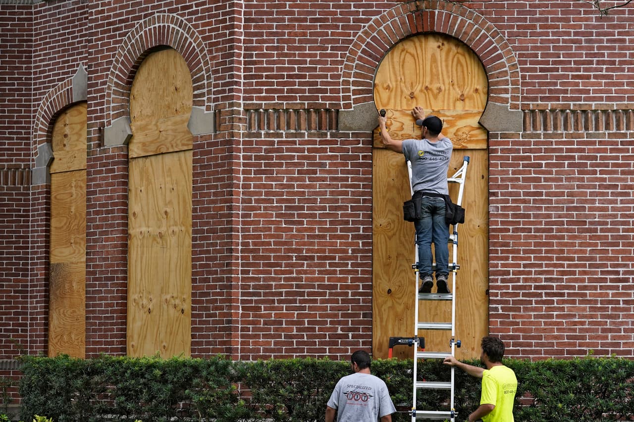 Personas tapan las ventanas del histórico Henry B. Plant Hall en el campus de la Universidad de Tampa antes del huracán Ian el martes 27 de septiembre de 2022, en Tampa, Florida.