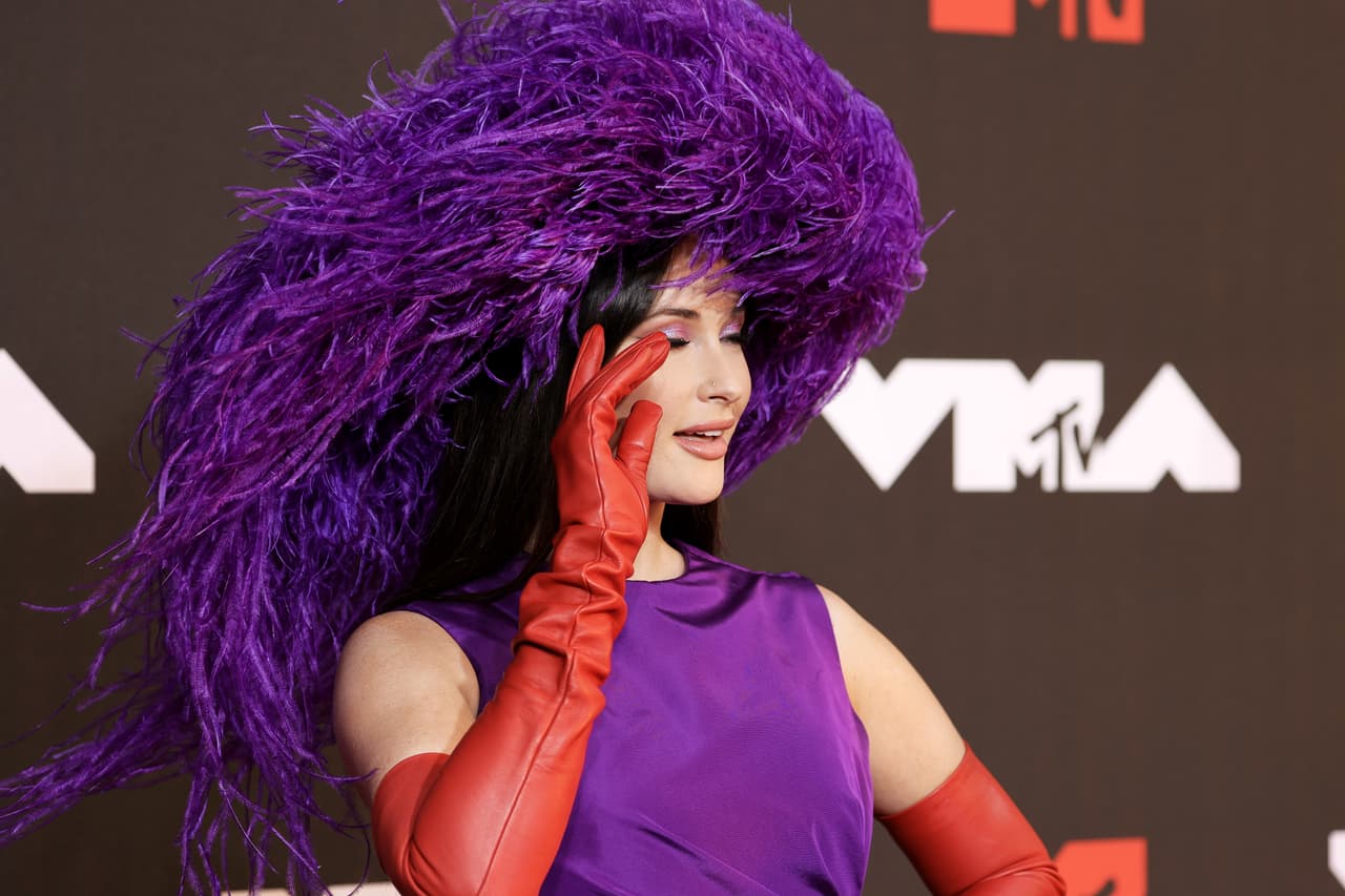Kacey Musgraves arribó con un tocado emplumado en color violeta, uno de los colores de mayor tendencia de la noche.