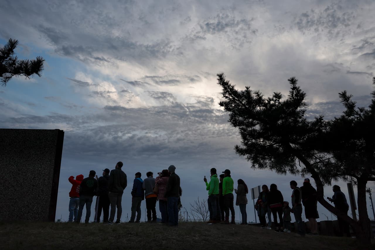 La gente se reúne para mirar desde lejos un carguero que chocó contra el puente Francis Scott Key y se derrumbó el 26 de marzo de 2024 en Baltimore, Maryland. Un equipo de trabajo estaba arreglando los baches en el puente cuando el carguero Dali chocó alrededor de la 1:30 de la madrugada del martes.