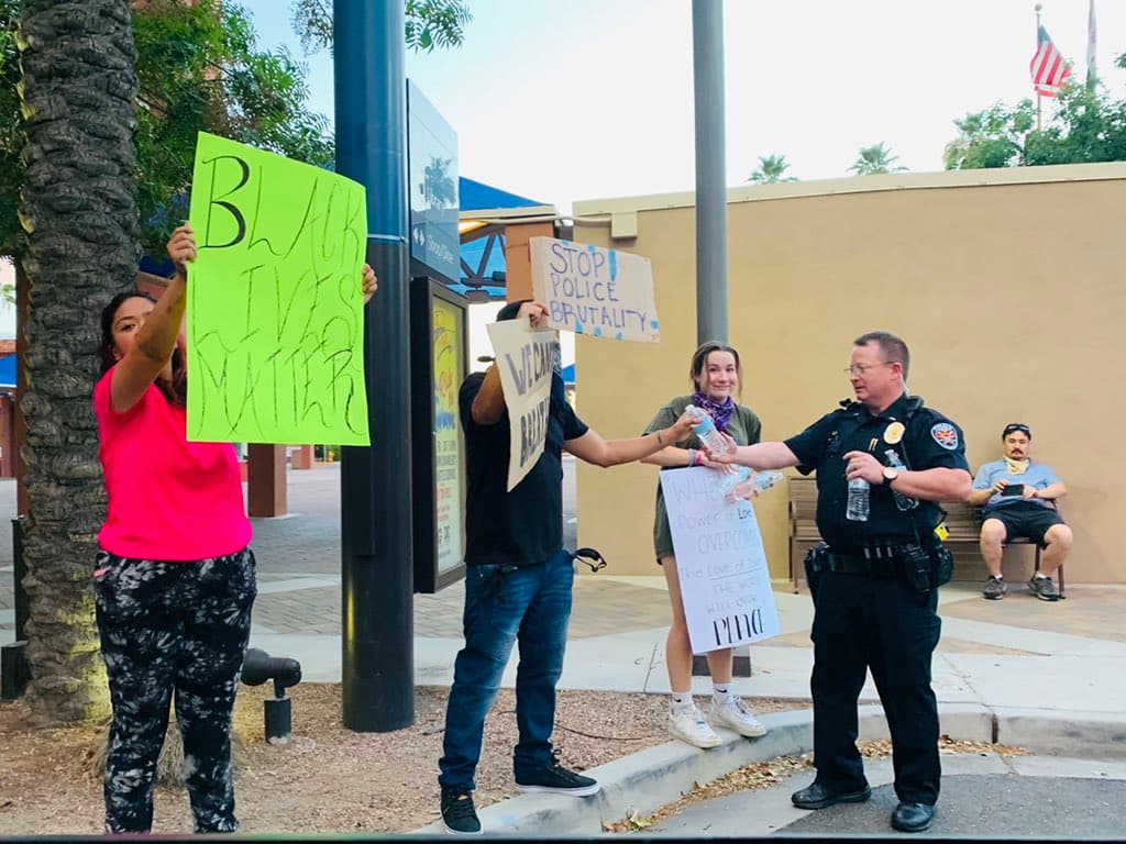 Un oficial reparte agua a miembros de la comunidad durante la protesta del 4 de junio en la avenida Arizona. 
<br>