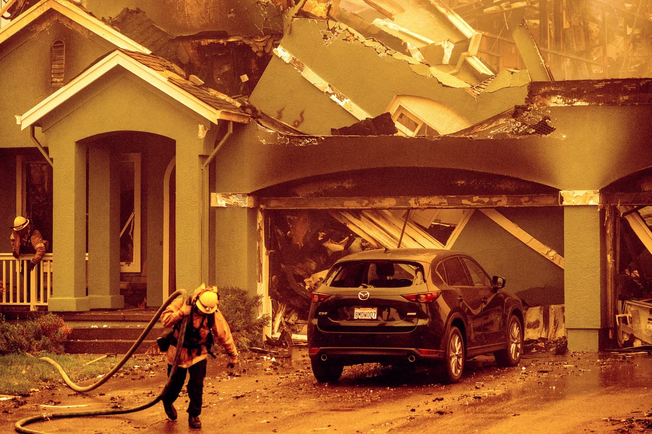 En la ciudad de Santa Rosa, el vecindario Skyhawk fue uno de los primeros golpeados por las llamas del incendio Glass. En la imagen, un bombero apaga las brasas de una vivienda que quedó semidestruida.