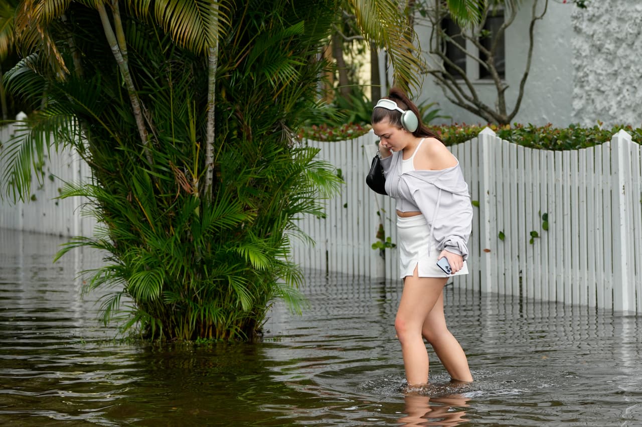 Un residente camina cuidadosamente hacia su casa a través de las vías inundadas en el vecindario Sailboat Bend de Fort Lauderdale, Florida, el jueves 13 de abril de 2023.