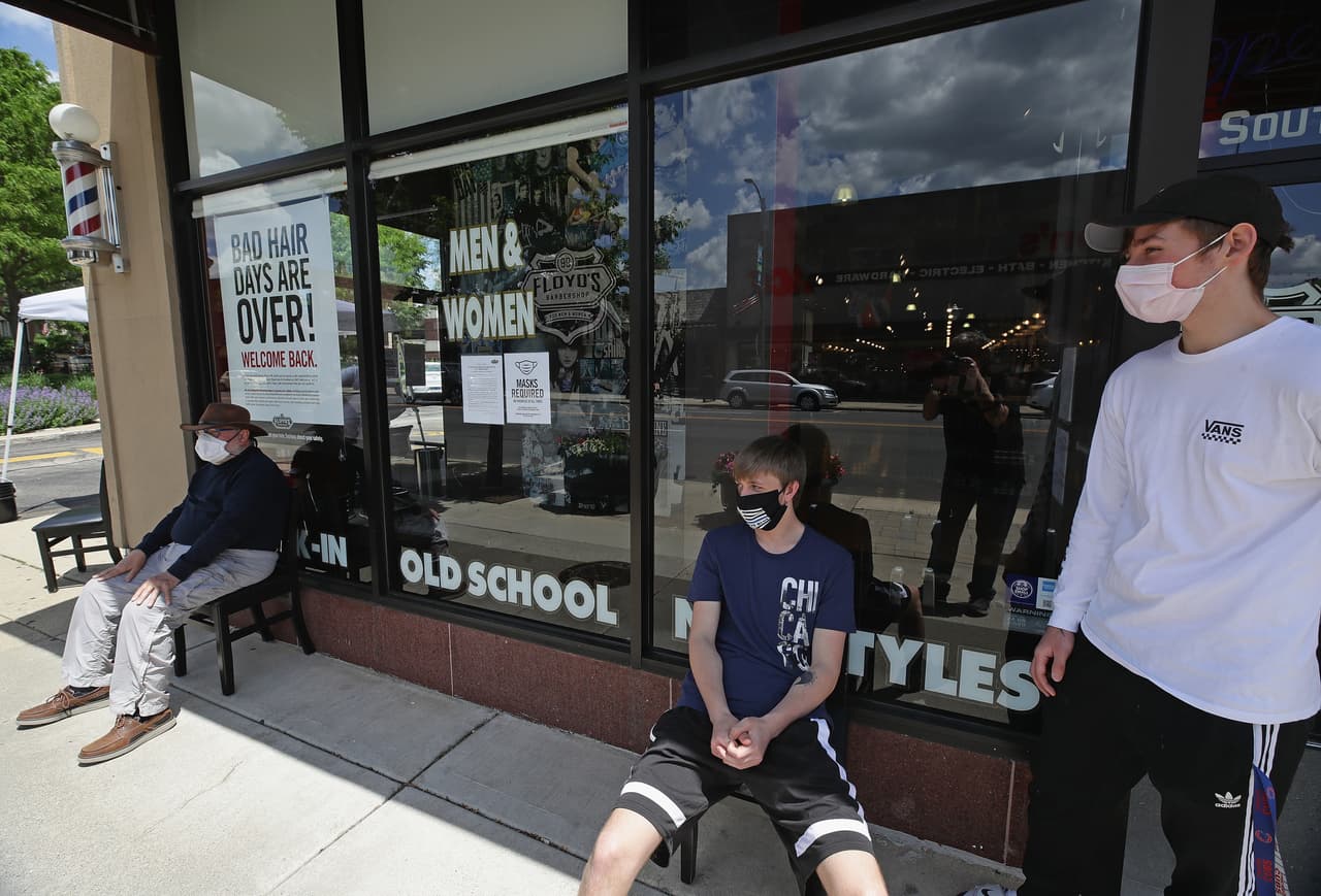 Clientes esperan cortarse el pelo en la barbería Floyds 99 en LaGrange. Los negocios no esenciales han estado cerrados por más de dos meses en Illinois.