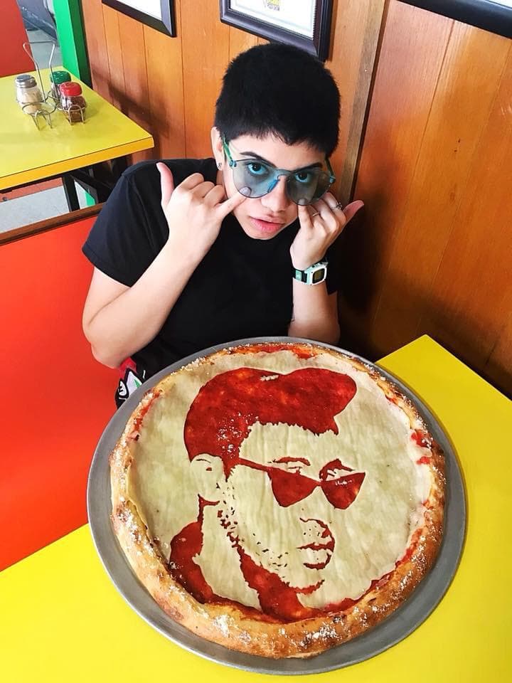 Un fanático posa con su pizza de Bad Bunny.