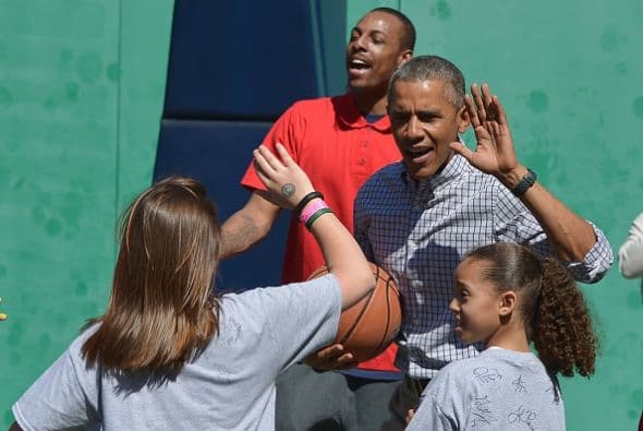 Obama choca sus palmas con los niños que forman parte de su equipo en un juego de baloncesto.
