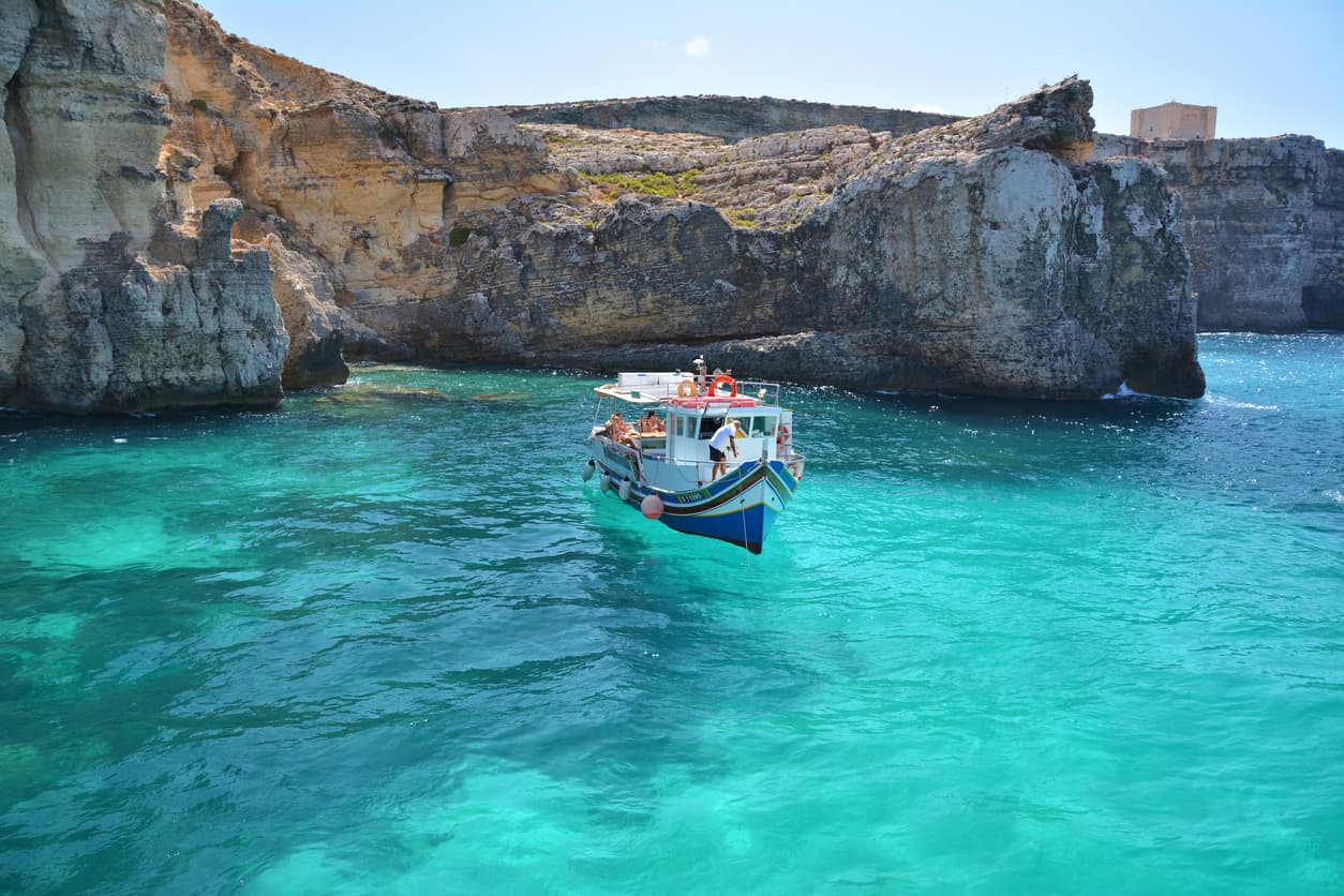 En la isla no circulan automóviles y, aparte de un hotel, está prácticamente deshabitada. En la imagen, un bote en la Laguna de Cristal de Comino. Al fondo se puede ver el perfil de la Torre de Saint Mary.