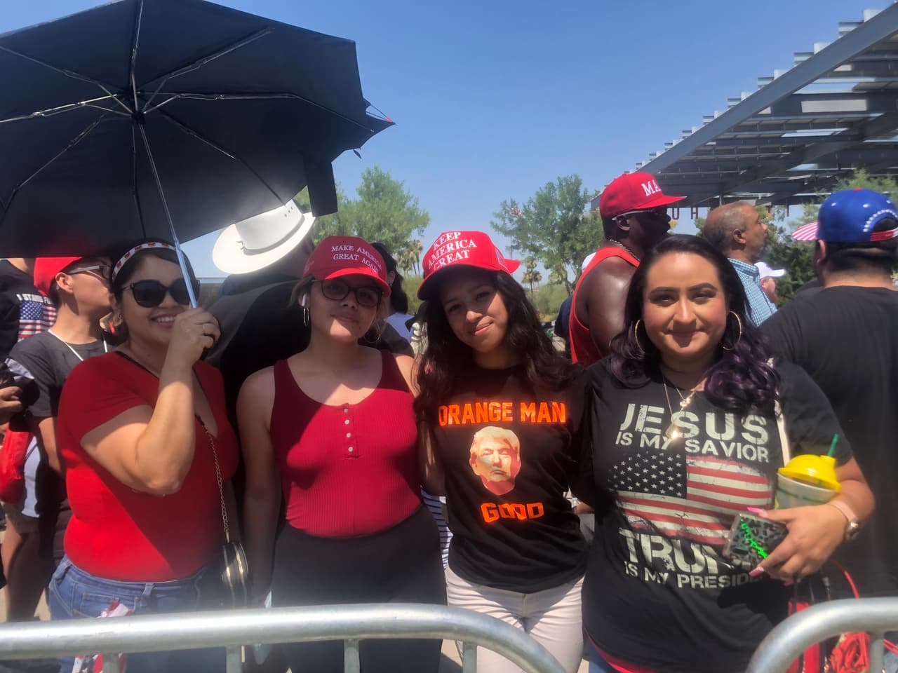 Un grupo de mujeres con gorras de la campaña de Trump hacen fila para ingresar al evento Estudiantes por Trump.