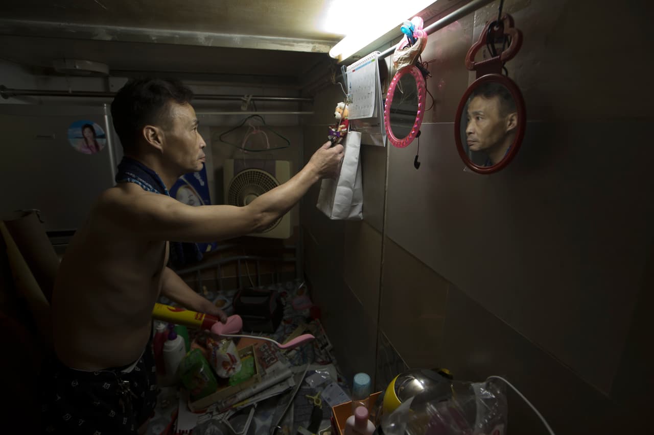 Sin, de 55 años, arregla sus pertenencias dentro de su "casa de ataúd" de Hong Kong