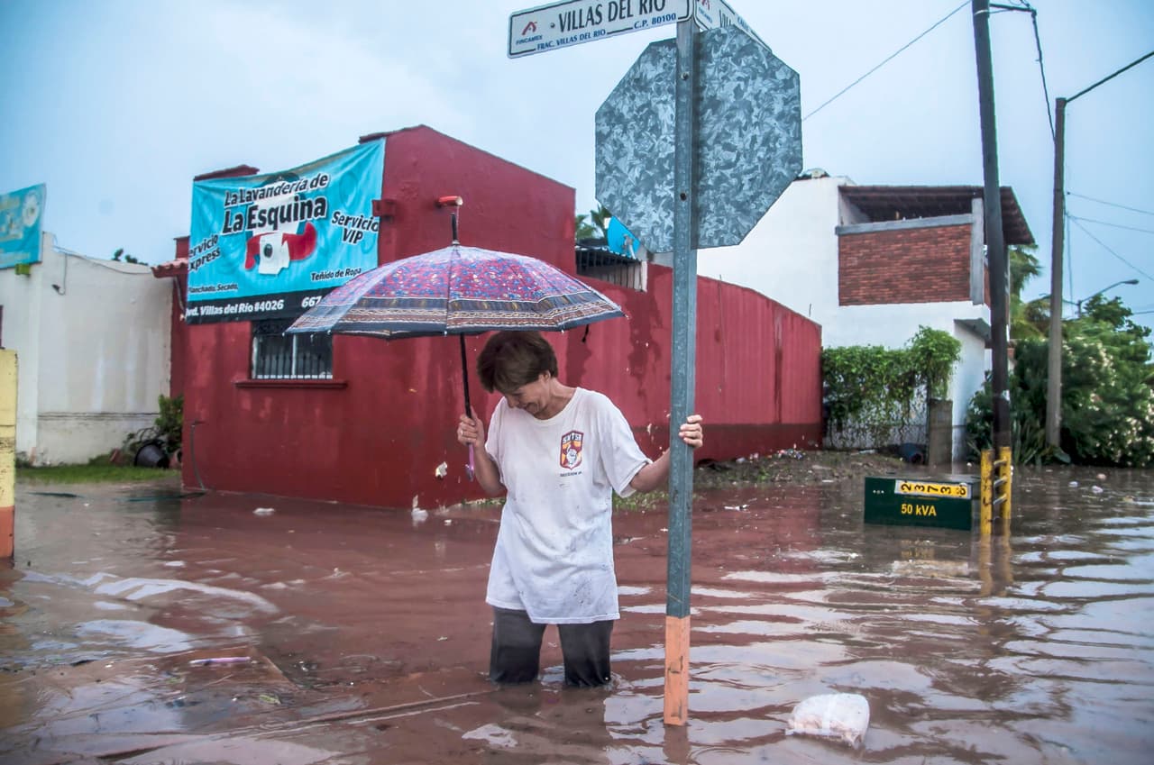 Una mujer intenta caminar por una calle inundada de Culiacán, una de las ciudades más afectadas por las lluvias. La depresión llamada E-19 se formó en el golfo de California hace dos días, según el
<a href="https://smn.cna.gob.mx/files/pdfs/comunicados-de-prensa/Comunicado545-18.pdf">Servicio Meteorológico Nacional de México (SNM).</a>