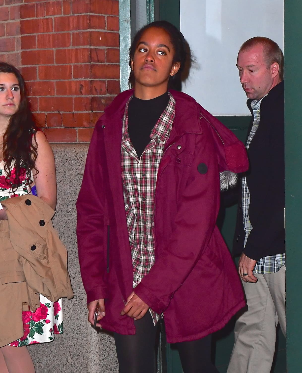 Malia Obama, un poco cansada de los paparazzis, luce un abrigo marrón, camisa a cuadros y su pelo cogido.