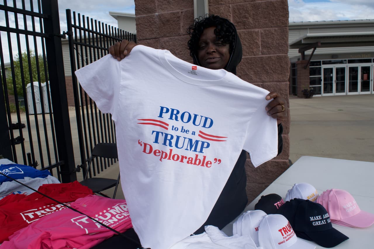 Beatrice Thomson, quien vino al mitín de Trump en Loveland, Colorado desde Carolina del Sur solo para vender mercancía, enseña el modelo de camiseta más popular: “Orgullosa de ser una deplorable de Trump”.
