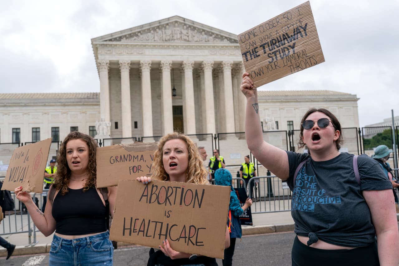 <b>"Aborto es atención en salud",</b> dice la pancarta de la mujer en el centro de la foto, que se postró este sábado frente al máximo tribunal junto a decenas de personas.