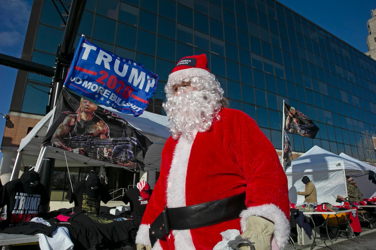 Un Santa Claus frente a los vendedores de parafernalia del presidente Donald Trump, en un auditorio donde celebró un mitin de campaña en Battle Creek, Michigan. 18 de diciembre de 2019.